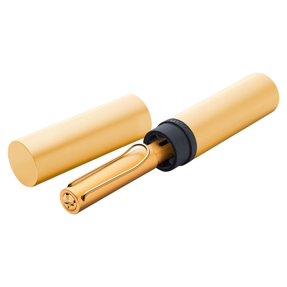 Un écrin ouvert contenant le stylo plume Lamy LX Aluminium Or est posé sur un fond blanc. L'écrin est élégant et minimaliste sous forme cylindrique, mettant en avant le stylo avec sa finition en aluminium doré, avec le logo de la marque clairement visible.