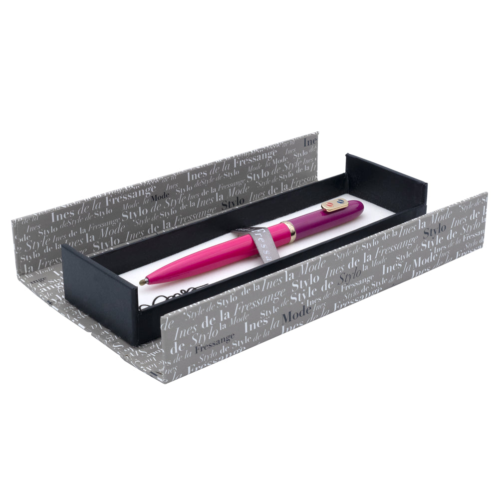 Un écrin ouvert du stylo roller rose fuchsia avec attributs dorés de la marque Inès de la Fressange est posé sur un fond blanc. L'écrin est visible dans son intégralité, mettant en avant son design.