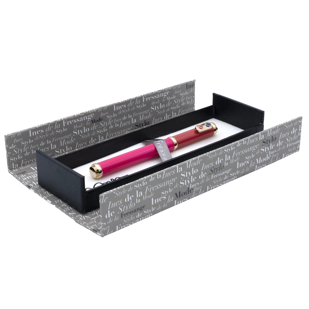 Un écrin ouvert du stylo plume rose rouge avec attributs dorés de la marque Inès de la Fressange est posé sur un fond blanc. L'écrin est visible dans son intégralité, mettant en avant son design.