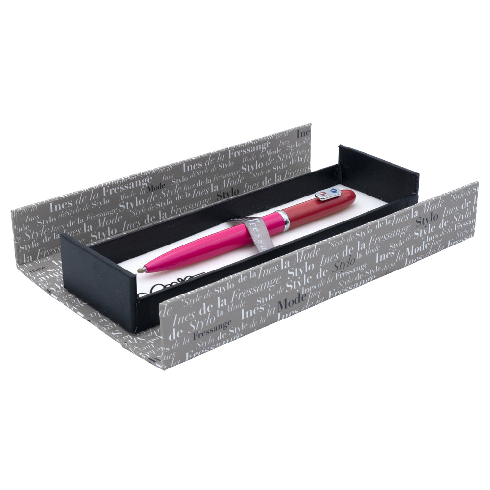 Un écrin ouvert du stylo roller rose rouge avec attributs chromés de la marque Inès de la Fressange est posé sur un fond blanc. L'écrin est visible dans son intégralité, mettant en avant son design.
