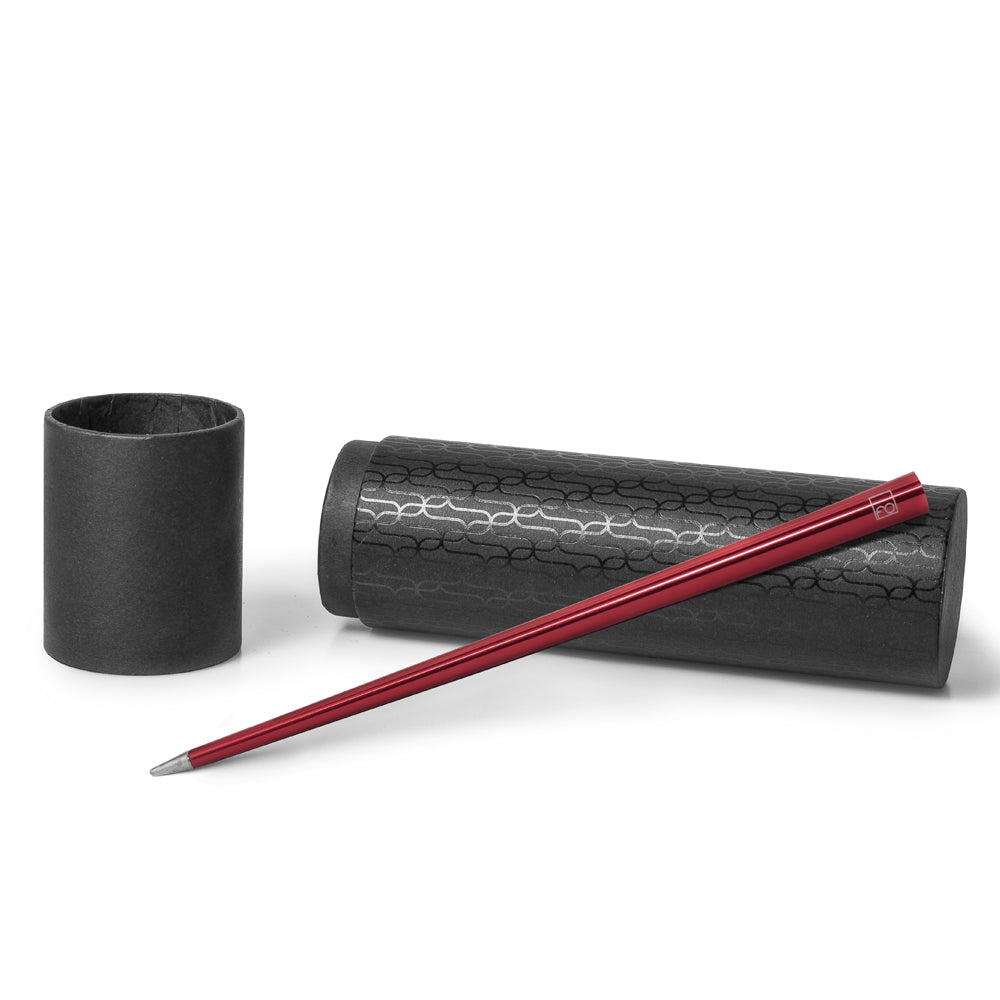 Stylo Forever Prima en rouge posé sur son écrin cylindrique noir avec des motifs, présenté sur un fond blanc. L'écrin cylindrique protège le stylo tout en mettant en valeur sa couleur rouge vive et son design moderne.
