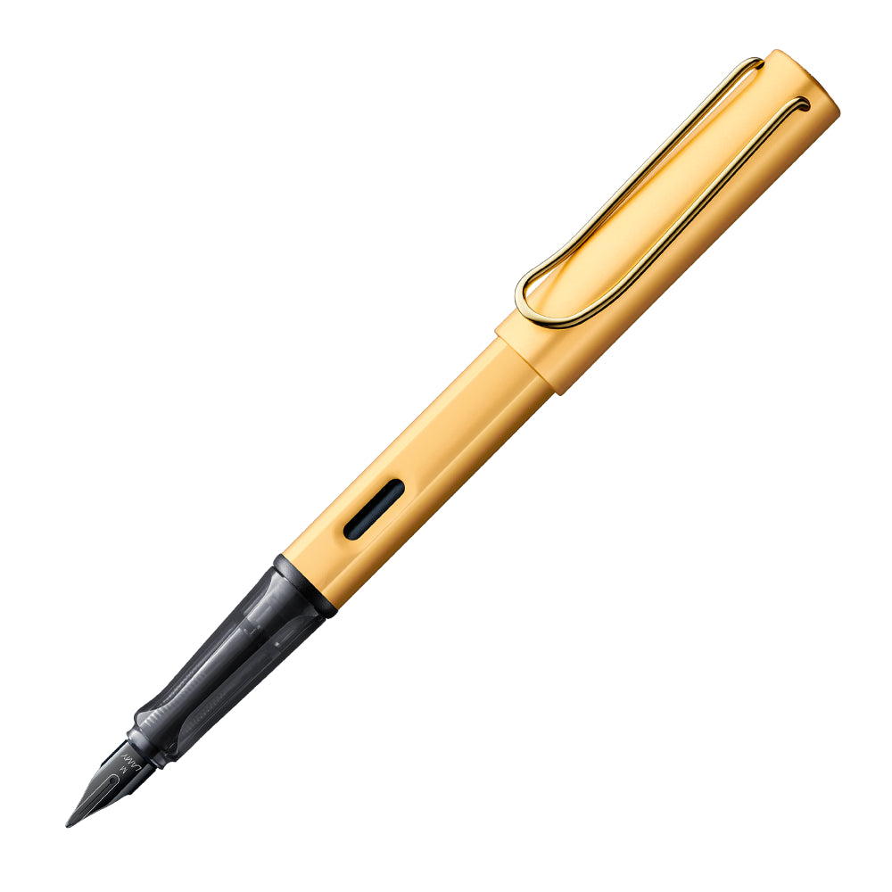 Un stylo plume Lamy LX en aluminium avec finition or, incliné à 45 degrés avec le bouchon retiré, est présenté sur un fond blanc. Le stylo plume se caractérise par son design raffiné en aluminium avec une élégante finition dorée, offrant une expérience d'écriture luxueuse et moderne.